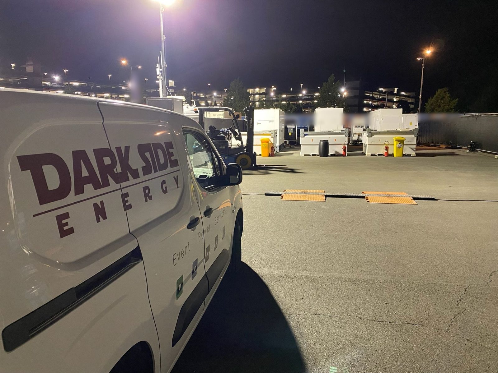 Dark Side Energy van at night in front of a generator park lit by a lighting tower